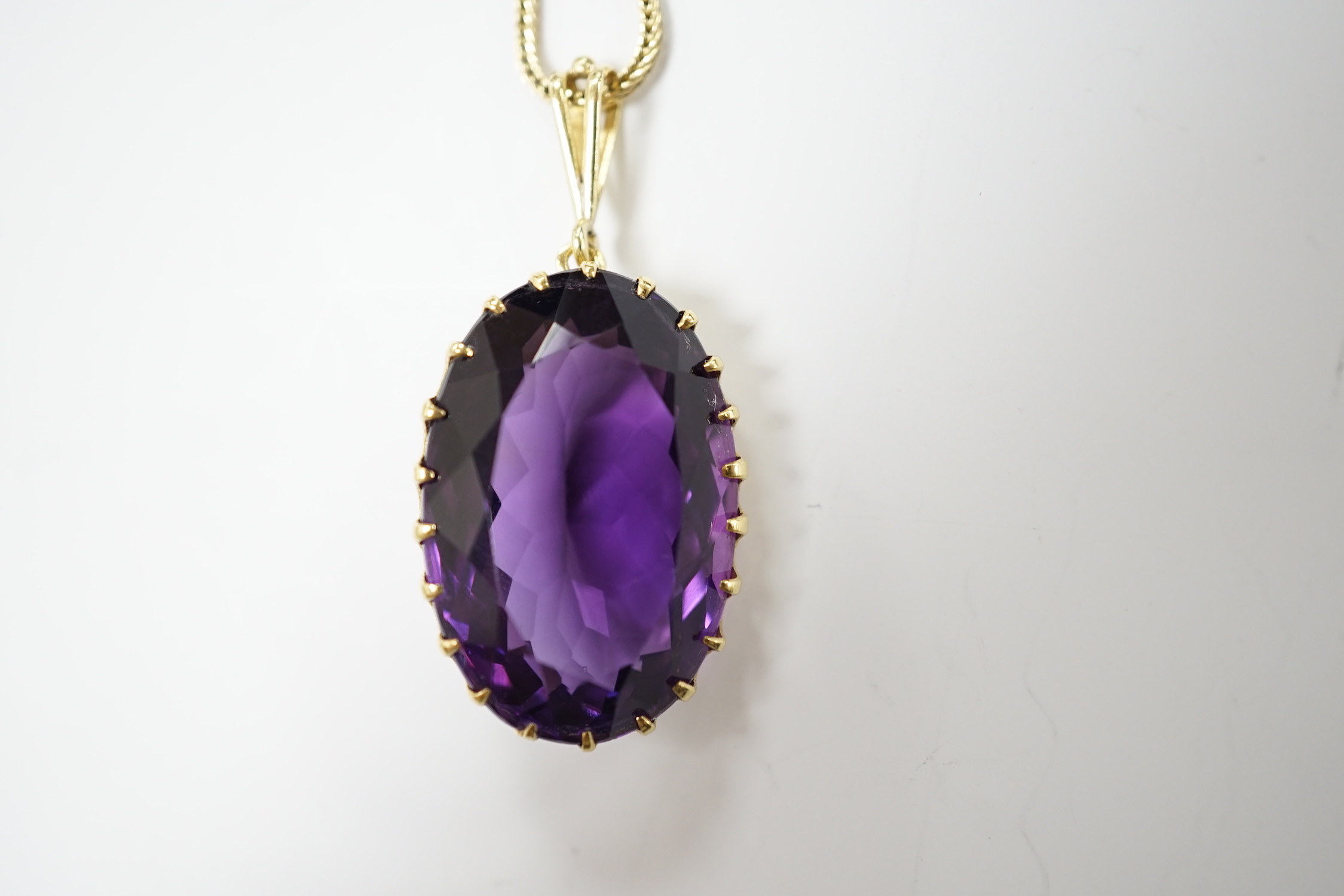 A yellow metal mounted single stone oval cut amethyst set pendant, 35mm, on a yellow metal chain, 48cm, gross weight 10.7 grams